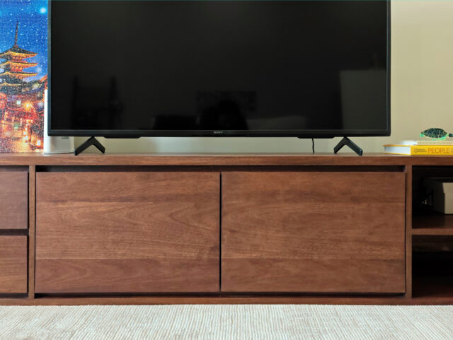 Continuous wood grain across TV cabinet doors and drawers, melunak dark walnut finish